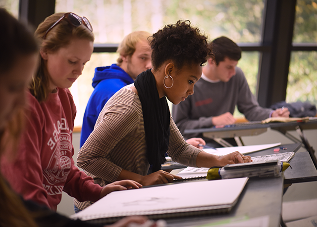 Several students focus on their drawings in class.